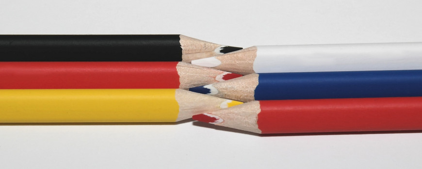 Buntstifte in Farben der deutschen und russischen Flagge, ineinander verschränkt