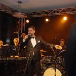 Sänger in schwarzem Anzug und Musiker mit Instrumenten