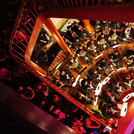 Treppenhauskonzert: Das akademische Blasorchester musiziert im Foyer des Nordcommuns. Das Publikum hockt auf den Stufen, bis hinauf in den dritten Rang.