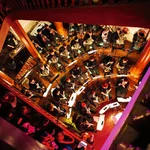 Treppenhauskonzert: Das akademische Blasorchester musiziert im Foyer des Nordcommuns. Das Publikum hockt auf den Stufen, bis hinauf in den dritten Rang.