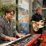 Ein Mann am Keyboard, im Hintergrund ein Mann mit Gitarre