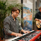 Ein Mann am Keyboard, im Hintergrund ein Mann mit Gitarre