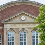 Fassade des Audimax der Universität Potsdam, links und rechts gesäumt von blühenden Kastanien