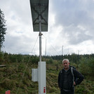 Foto: Scientist Marek Zreda standing next to a Lab-C CRNS probe with shubrs and forest in the background and cloudy sky | Foto: Cosmic Sense consortium