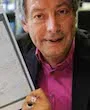 Ottmar Ette schaut in die Kamera und zeigt ein Faksimileblatt der Tagebücher