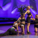 Vier weibliche Personen in unterschiedlichen Tanzpositionen auf einer Bühne
