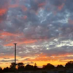 Ein Himmel mit lockeren, tief stehenden Wolken wird von der unter gehenden Sonne in ein zauberhaftes Lichtspiel getaucht.