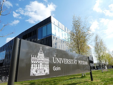 Froschperspektive auf das Bibliotheksgebäude mit dem Eingangsschild der Uni