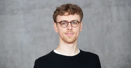 Mann mit kurzen, blonden Haaren und runder Brille.