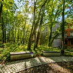 Two benches in front of trees, behind them the portal of a large house