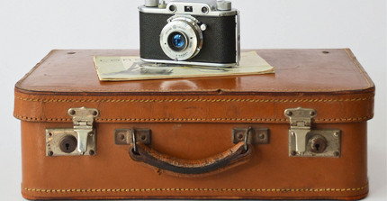 A suitcase and an old camera on top of it.