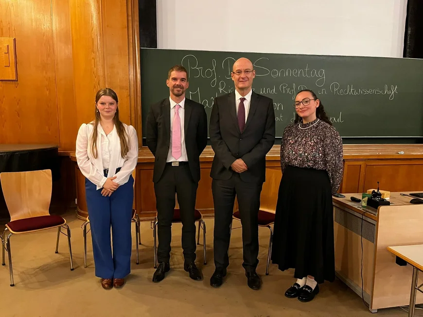 Auf dem Bild sieht man die vier Teilnehmer der Podiumsdiskussion nebeneinander aufgestellt.