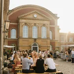 Ein Blick in den Innenhof von Haus 8 mit stimmungsvollem Abendlicht: Viele Menschen in vielen Gruppen tauschen sich aus.