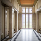 Large multilevel foyer made of marble with high windows in the background