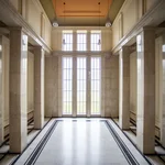 Großes, mehrstöckiges Foyer aus Marmor mit hohen Fenstern im Hintergrund