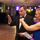 Eine Frau in blauem Overall hält ein Mikrofon vor einen Mann.