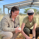 NamTip researchers sitting in front of an opened Diviner probe (white pipe emerging from the soil) under the roof of the TipEx experiment