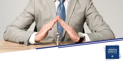 Mann im Anzug schützt mit seinen Händen eine Glühbirne