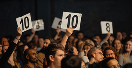 Beim Science Slam halten Zuschauer ihre Punktwertung hoch.