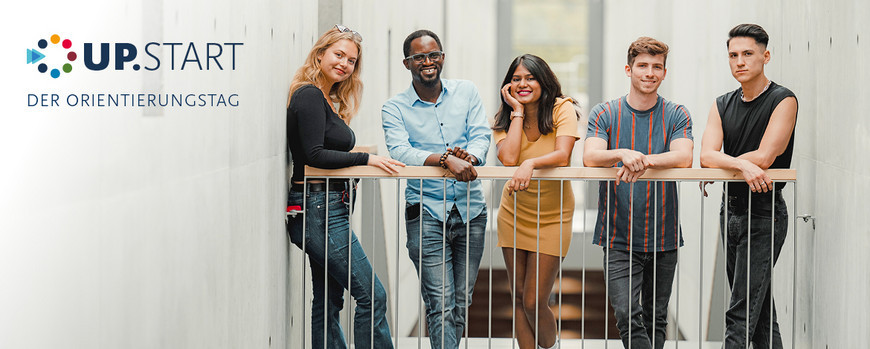 Studierende, die in die Kamera lächeln und an einem Geländer stehen