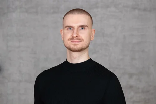 Mann mit kurzen Haaren und schwarzem Pullover.