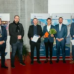 Sechs männliche Personen auf einem Podium