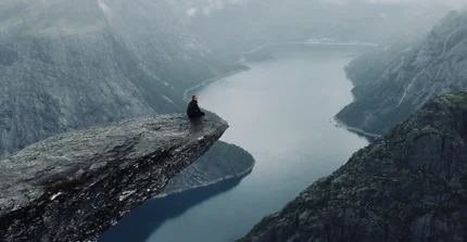 Student sitzt auf Berg in Norwegen