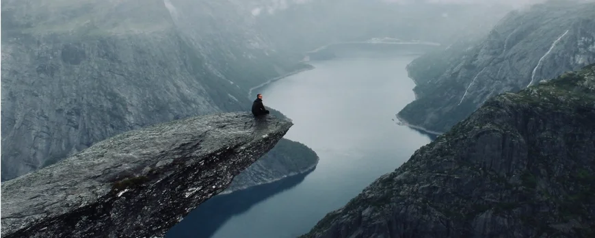 Student sitzt auf Berg in Norwegen