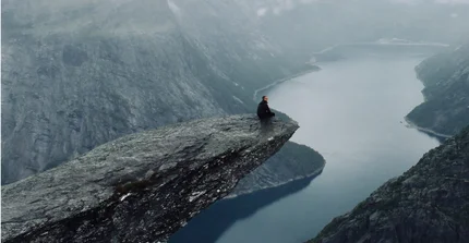 Student sitzt auf Berg in Norwegen