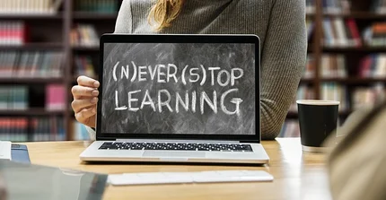 Ein Laptop aufgeklappt, auf dem Bildschirm steht: (N) EVER (S) TOP LEARNING