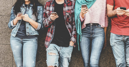 Menschen lehnen an der Wand mit Mobiltelefonen in der Hand