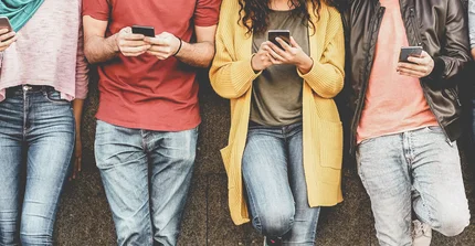 Menschen lehnen an der Wand mit Mobiltelefonen in der Hand