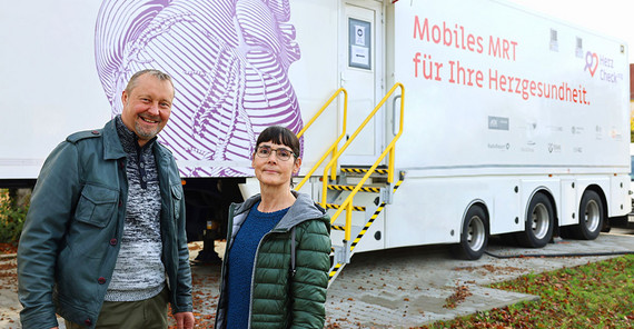 Zwei Personen stehen vor dem Herzcheck-Truck mit dem Aufdruck "Mobiles MRT für Ihre Herzgesundheit"