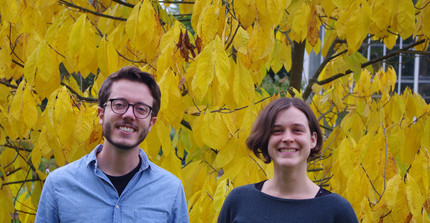 Portrait picture of Thomas Bringhenti and Ildikó Orbán in front of a tree with yellow leaves