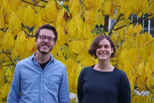 Portrait picture of Thomas Bringhenti and Ildikó Orbán in front of a tree with yellow leaves