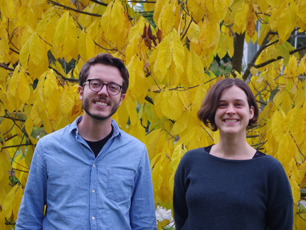 Portrait picture of Thomas Bringhenti and Ildikó Orbán in front of a tree with yellow leaves
