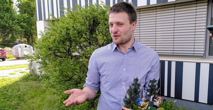 Daniel Rasche hält seinen neuen Doktorhut in den Händen. Darauf sind kleine Bäume, ein See, CRNS Sensoren und kosmische Stahlen sowie eine Spielzeugfigur mit Cowboyhut zu sehen | Foto: Cosmic Sense Konsortium