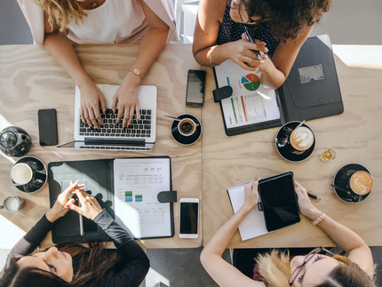 Vier Frauen arbeiten gemeinsam an einem Tisch.