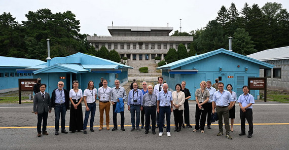 Gruppenfoto der deutschen Delegation und ihren Betreuern an der Grenze, im Hintergrund Nordkorea.