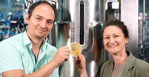 Dr Lena Hochrein and Professor Ruben R. Rosencrantz are holding up a Petri dish covered in growth.