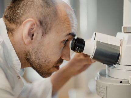 Mann der in ein Mikroskop schaut