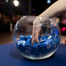 Eine Glasschale mit blauen Jetons und eine Hand, die hinein greift.