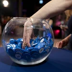 Eine Glasschale mit blauen Jetons und eine Hand, die hinein greift.
