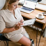 Eine junge Frau arbeitet an ihrem Tablet und hat eine Beinprothese. 