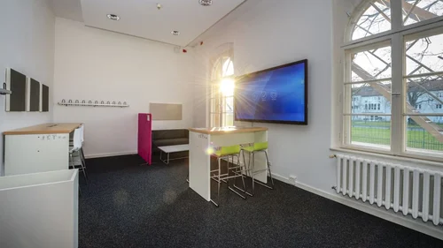 Blick in eine Selbstlernzone am Campus Neues Palais mit diversen Tischen, Sitzmöglichkeiten und einem Bildschirm