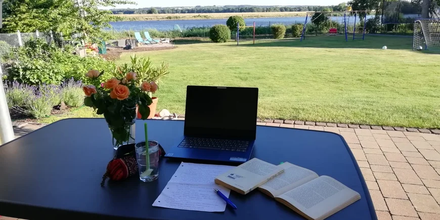 Schreibtisch mit Rosen mit Blick auf Wiese und See