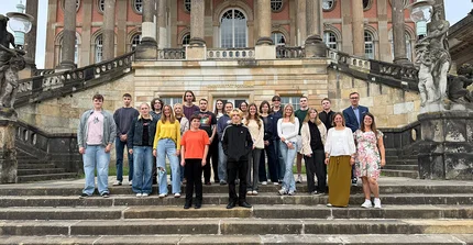 Gruppenfoto der neuen Auszubildenden und Ausbildungsleitung auf den Treppen an den Communs am Neuen Palais.