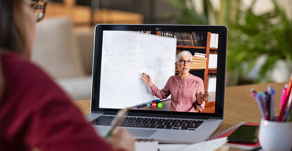 Person sitzt am Schreibtisch vor einem Laptop und verfolgt ein Zoom-Meeting. Das Foto ist von AdobeStock/Rido.