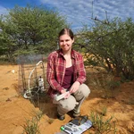 NamTip researcher sitting in front of savanna shrubs with measuring devices, a book and a pen