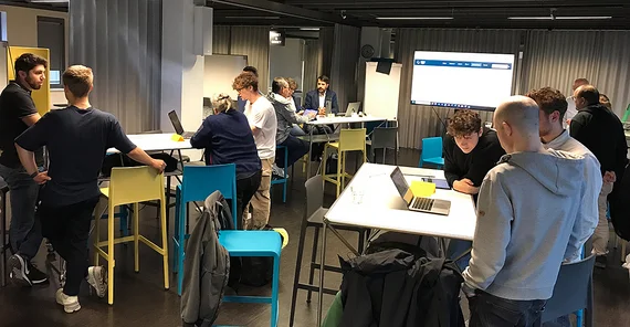 People are standing at tables in a room and talking to each other.